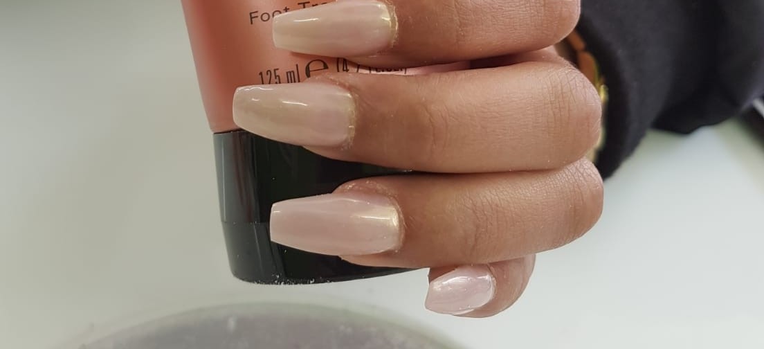 Lange nude nagels in coffin-vorm, op de manicuretafel
